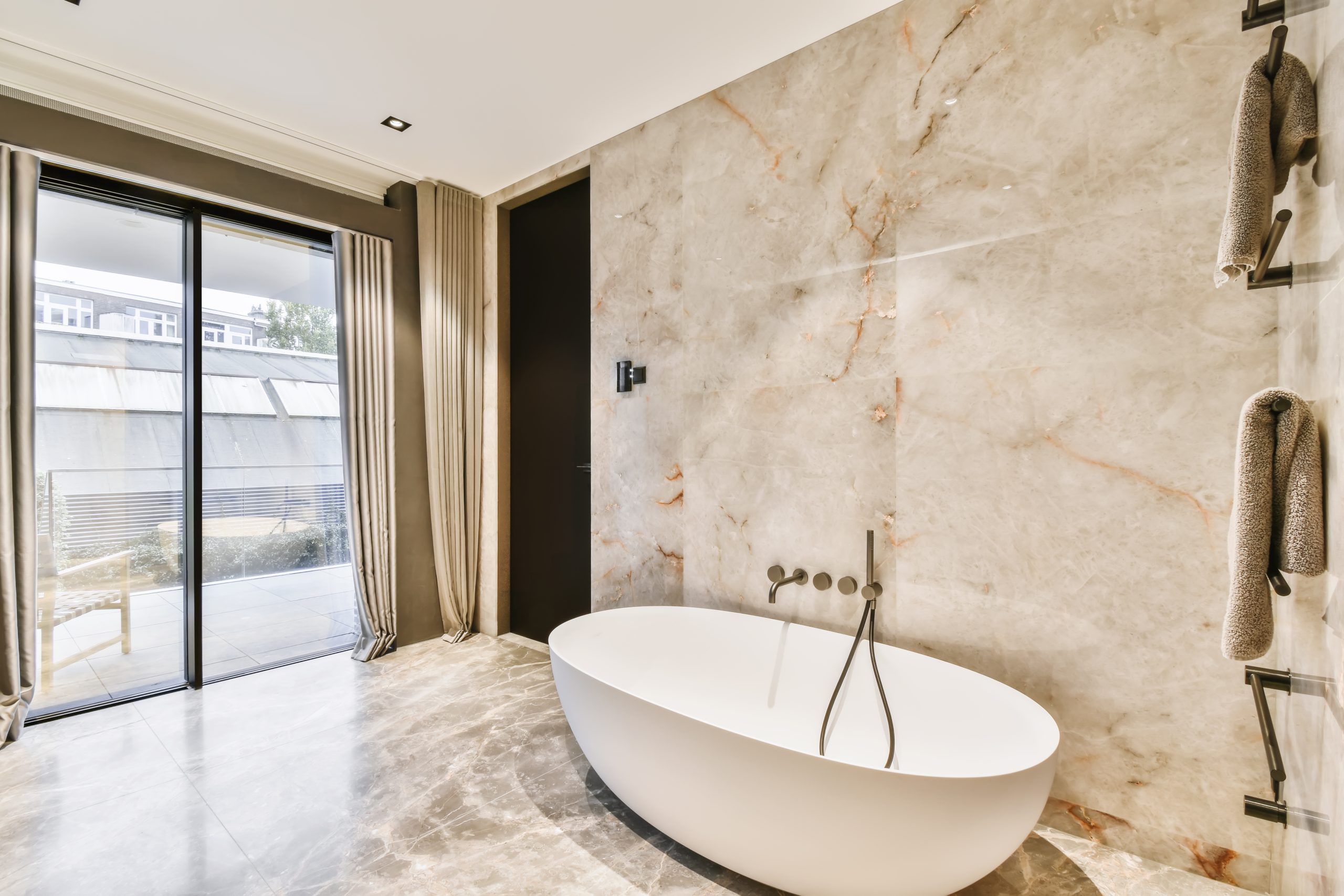 Attractive bathroom with oval bathtub and marble floor and walls
