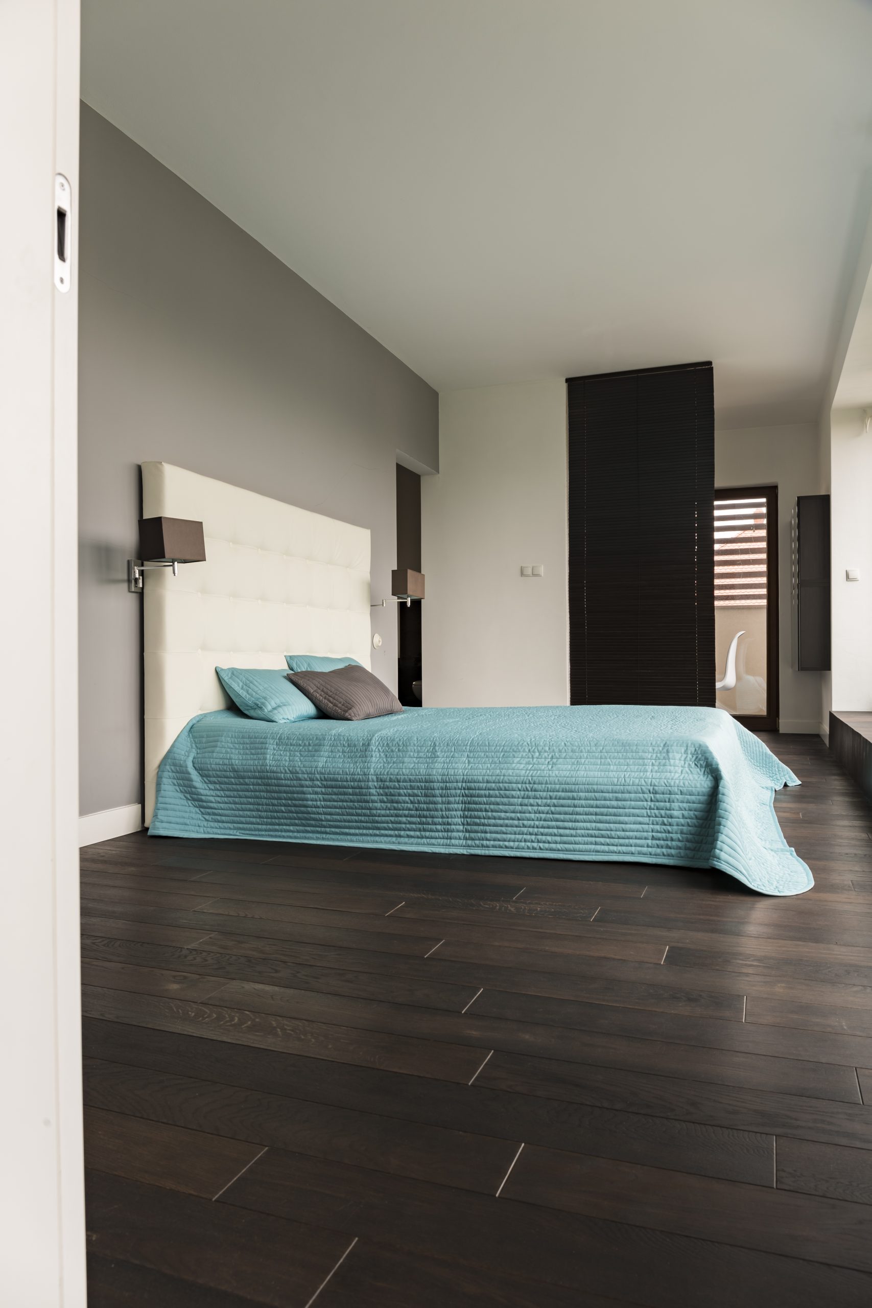 Spacious bedroom with wooden floor and white walls