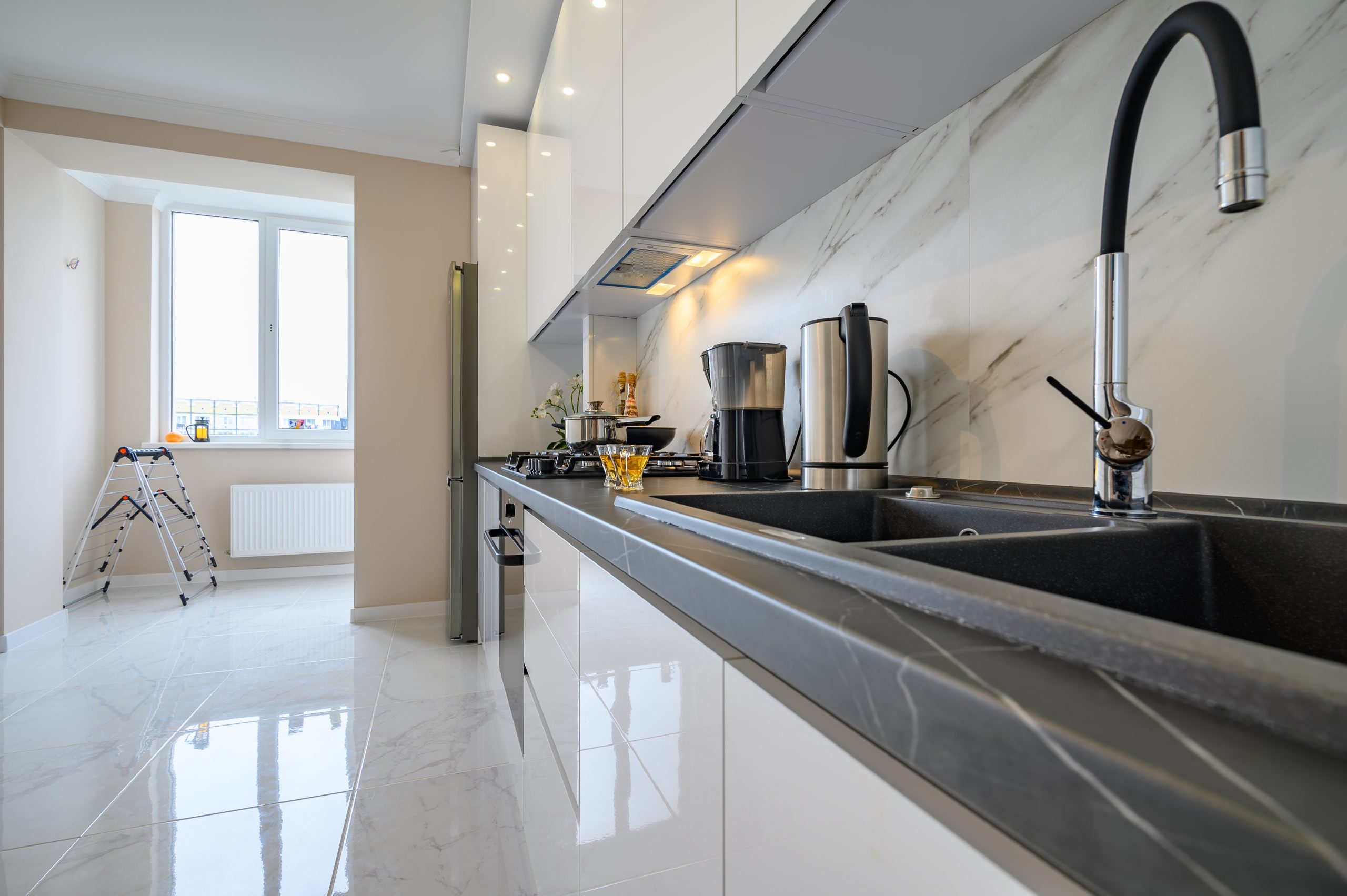 Closeup to modern kitchen cupboard with electric kettle, coffee maker and two glass cups of tea