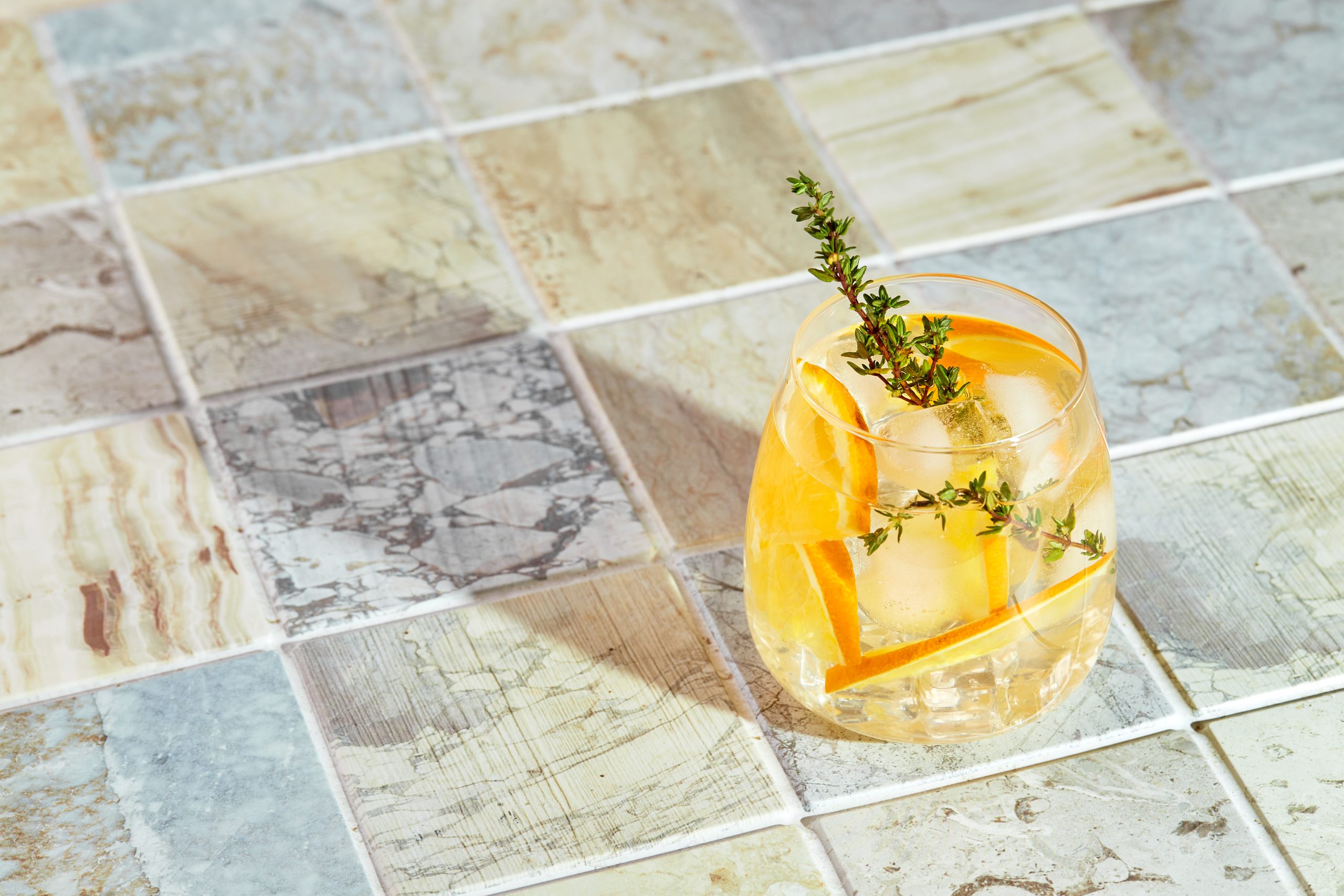 Refreshing cocktail with ice, orange and thyme. Refreshing summer homemade alcoholic or non-alcoholic cocktail or mocktail, or Detox infused flavored water.