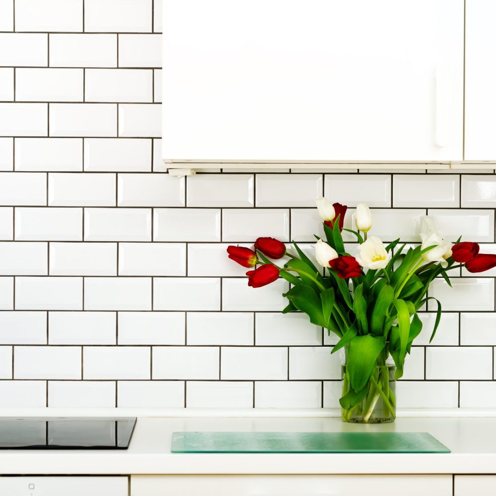 Fresh bouquet of red and white tulips on kitchen table. Detail of home interior, design. Minimalistic concept. Flowers for mother, girl, woman. Copy space