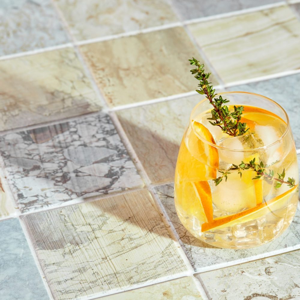 Refreshing cocktail with ice, orange and thyme. Refreshing summer homemade alcoholic or non-alcoholic cocktail or mocktail, or Detox infused flavored water.